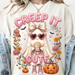 May include: A white crewneck sweatshirt featuring a graphic of a ghost wearing a large bow, heart-shaped sunglasses, and pink sneakers. The ghost holds a cup labeled PSL. The text reads CREEP IT CUTE, surrounded by flowers, pumpkins, and bats.