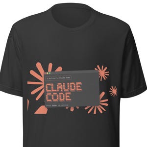 May include: Black t-shirt featuring a graphic of a computer window with the text "CLAUDE CODE" in a retro font. The design includes coral-colored starburst shapes. The text "Press Enter to continue" is also visible.