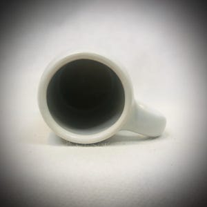 May include: A set of three ceramic mugs with a speckled, matte finish. The mugs are in shades of cream, light gray, and dark gray. Each mug has a simple, minimalist design, perfect for coffee or tea.