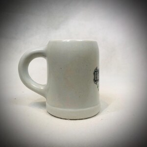 May include: A set of three ceramic mugs with a speckled, matte finish. The mugs are in shades of cream, light brown, and dark brown. Each mug has a simple, minimalist design and a rounded handle.