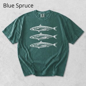May include: A blue spruce t-shirt featuring a white illustration of three fish. The short-sleeved shirt has a crew neck and a slightly faded appearance. The text "Blue Spruce" is at the top of the image.