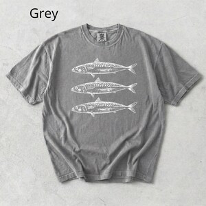May include: Grey t-shirt with a crew neck featuring three white fish illustrations. The word "Grey" is printed in the upper left corner. The shirt is made of a soft material.