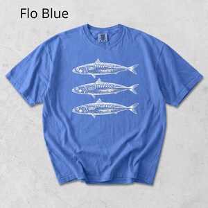 May include: A blue t-shirt with a white graphic of three fish. The text "Flo Blue" is in the upper left corner. The shirt has short sleeves and a crew neck.