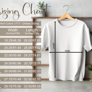 May include: White t-shirt hanging on a wooden rack, displaying a sizing chart. The chart includes measurements in inches and centimeters for sizes S through 4XL. The text reads "Sizing Chart" and "Comfort Colors 1717 - Unisex Sizing."
