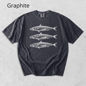 May include: Graphite-colored t-shirt featuring a detailed white illustration of three fish. The design is centered on the front of the shirt. The shirt has a classic crew neck and short sleeves. The word "Graphite" is printed in the upper left corner.