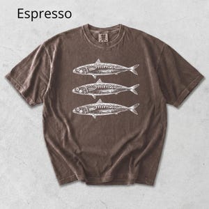 May include: Espresso-colored t-shirt featuring a graphic of three fish in white. The short-sleeved shirt has a crew neck and a vintage, washed appearance. The word "Espresso" is printed in the upper left corner.