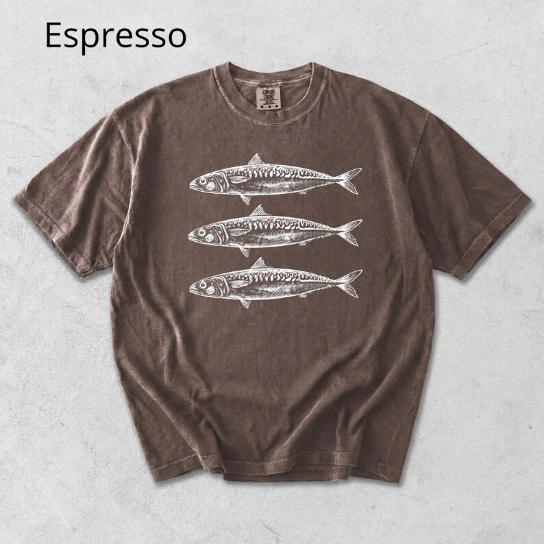 May include: Espresso-colored t-shirt featuring a graphic of three fish in white. The short-sleeved shirt has a crew neck and a vintage, washed appearance. The word "Espresso" is printed in the upper left corner.