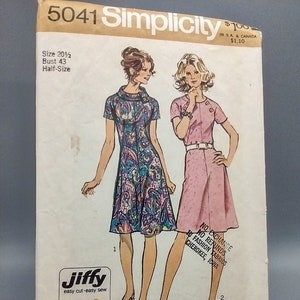 May include: A sewing pattern for a dress, Simplicity pattern number 5041, size 20 1/2, bust 43, half-size. The pattern includes two illustrations of women wearing dresses, one in a floral print and one in a solid pink. The pattern is labeled "Jiffy easy cut easy sew" and includes three main pattern pieces.