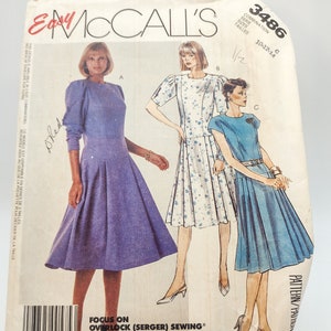 Puede incluir: Un patrón de costura vintage para un vestido con tres estilos diferentes. El patrón es para las tallas 10-12-14 y se llama "Easy McCall's" con el número 3486. El patrón muestra tres estilos diferentes de un vestido, uno con mangas largas, otro con mangas cortas y otro con mangas cortas. El vestido es un estilo simple, de línea A, con una falda plisada.