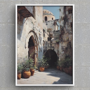 Może przedstawiać: Oprawiony wydruk przedstawiający scenę z uliczki. Grafika przedstawia stare kamienne budynki z łukowatymi drzwiami i kopulastą strukturą w tle. Doniczkowe rośliny obramowują chodnik, a paleta kolorów jest stonowana z ciepłymi tonami.