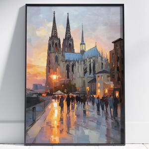 May include: Framed art print of a European cathedral at sunset. The painting depicts the cathedral's spires and architecture, with figures walking along a wet street. The sky is a blend of orange and blue hues.