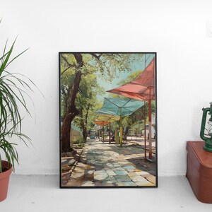 Puede incluir: Impresi&oacute;n art&iacute;stica enmarcada que representa un camino empedrado soleado bordeado de sombrillas de colores. La pintura presenta una paleta vibrante de verdes, azules y rojos, creando una escena exterior serena. La obra est&aacute; enmarcada en negro.