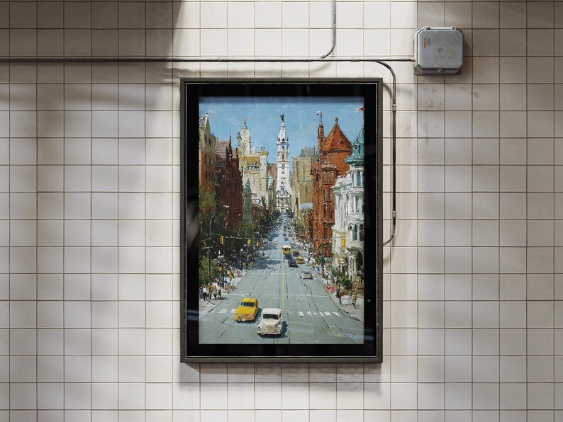 May include: A framed painting of a city street scene, featuring buildings in shades of brown, red, and white. The artwork depicts a long road with cars and trees, under a blue sky. The frame is black, and the background is a tiled wall.