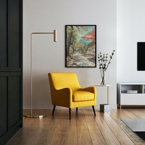 Puede incluir: Un sal&oacute;n moderno con un sill&oacute;n amarillo con patas negras, una l&aacute;mpara de pie dorada y una obra de arte enmarcada que representa una escena callejera. Una mesa auxiliar blanca con un jarr&oacute;n con flores. El suelo es de madera.