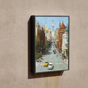 May include: A framed painting depicts a city street scene with buildings and cars. The artwork features a perspective view down a city street with yellow and white cars. The buildings are in shades of brown, red, and white, under a blue sky.