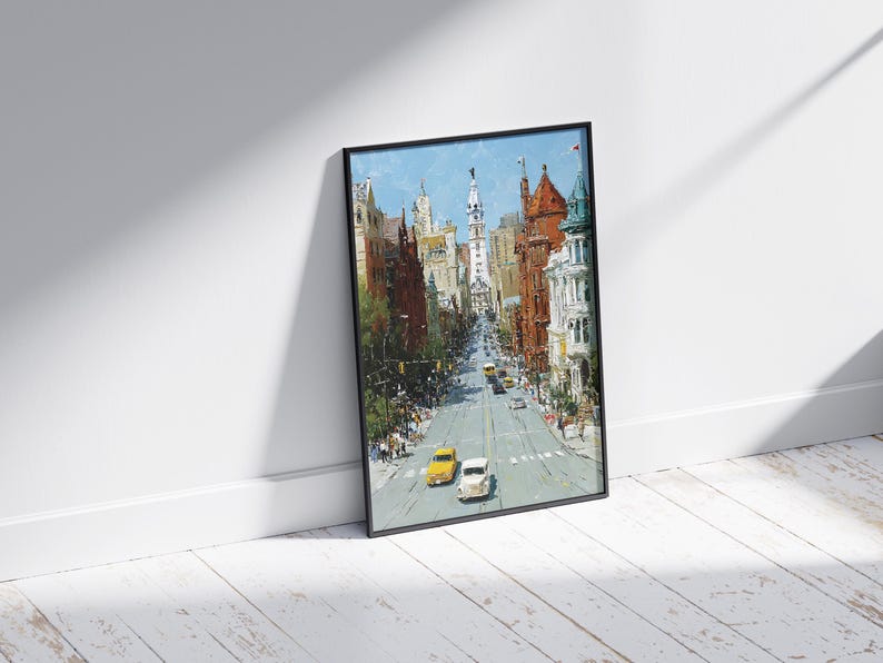May include: A framed art print depicting a city street scene. The painting features a perspective view of a street lined with buildings in shades of brown, red, and white. Yellow and white cars are on the road. The sky is blue.