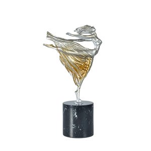 Könnte beinhalten: Silber- und goldfarbene Skulptur einer tanzenden Figur in Bewegung, mit fließenden Stoffen. Die Skulptur ist auf einem zylindrischen Sockel aus schwarzem Marmor montiert. Die Form der Figur fängt Bewegung und Anmut ein. Der Sockel hat etwa 7.6 cm Durchmesser.