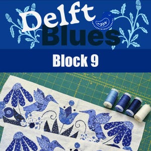 May include: A fabric panel with blue and white floral and bird designs, with the text "Delft Blues Block 9". Several spools of blue thread are arranged on a green cutting mat.