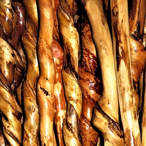 May include: Close-up of a group of twisted wooden sticks, showing the intricate grain patterns and natural variations in color. The wood is a rich brown and gold, with some areas of darker brown and red. The sticks are arranged in a random pattern, creating a visually interesting texture.