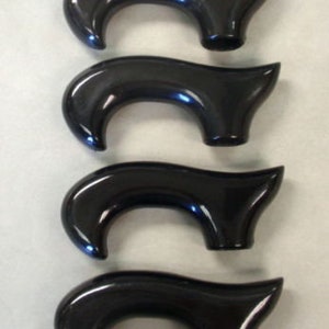 May include: Four black cane handles with a curved design. The handles are made of a smooth, glossy material.