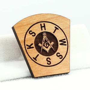 May include: Wooden Masonic compass and square with the letters "K.S.H.T.W.S." around the edge.
