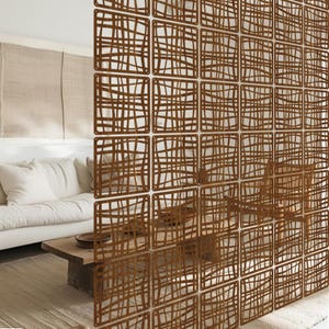 Può includere: Un divisorio decorativo con un motivo ripetuto di pannelli quadrati. Ogni pannello presenta un design traforato marrone di linee intersecanti, creando un aspetto strutturato a griglia. Il divisorio aggiunge un elemento moderno e artistico agli spazi interni.