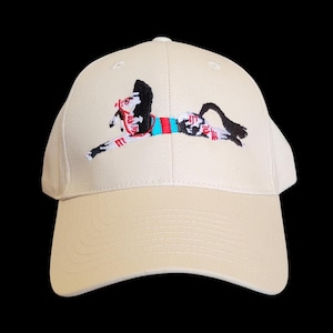 Op de afbeelding: Beige baseballpet met een geborduurd ontwerp van een rennend paard. Het paard heeft rode, zwarte en blauwe accenten. De pet heeft een gebogen klep en een knoop aan de bovenkant.