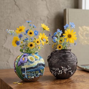 May include: Two round ceramic vases holding bouquets of yellow and blue flowers. The left vase features a colorful, textured relief design with swirling patterns and purple iris motifs. The right vase is dark gray with intricate, wavy line textures.