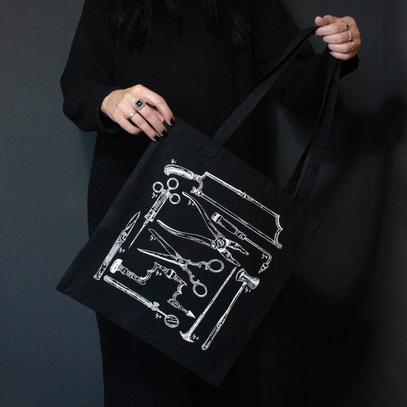 Schwarze Tragetasche mit einer weißen Illustration verschiedener chirurgischer Instrumente. Die Werkzeuge umfassen Sägen, Scheren und andere medizinische Instrumente. Die Tasche hat schwarze Griffe und besteht aus robustem Material.