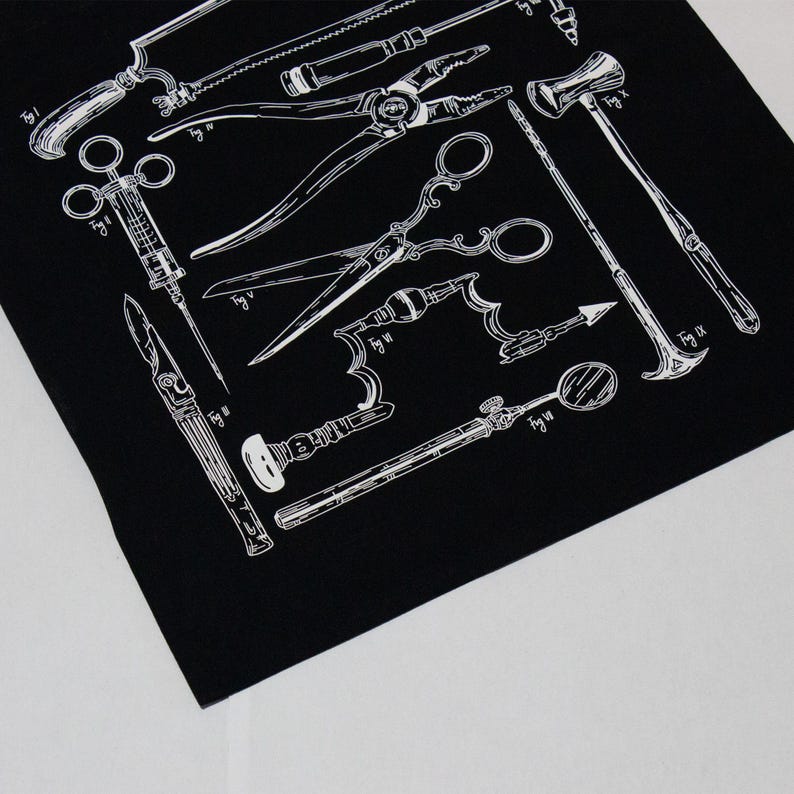 Schwarzer Stoff mit einer weißen Illustration von chirurgischen Werkzeugen im Vintage-Stil, darunter Sägen, Scheren und Zangen. Das Design zeigt detaillierte Strichzeichnungen verschiedener medizinischer Instrumente und schafft ein klassisches, anatomisches Thema.
