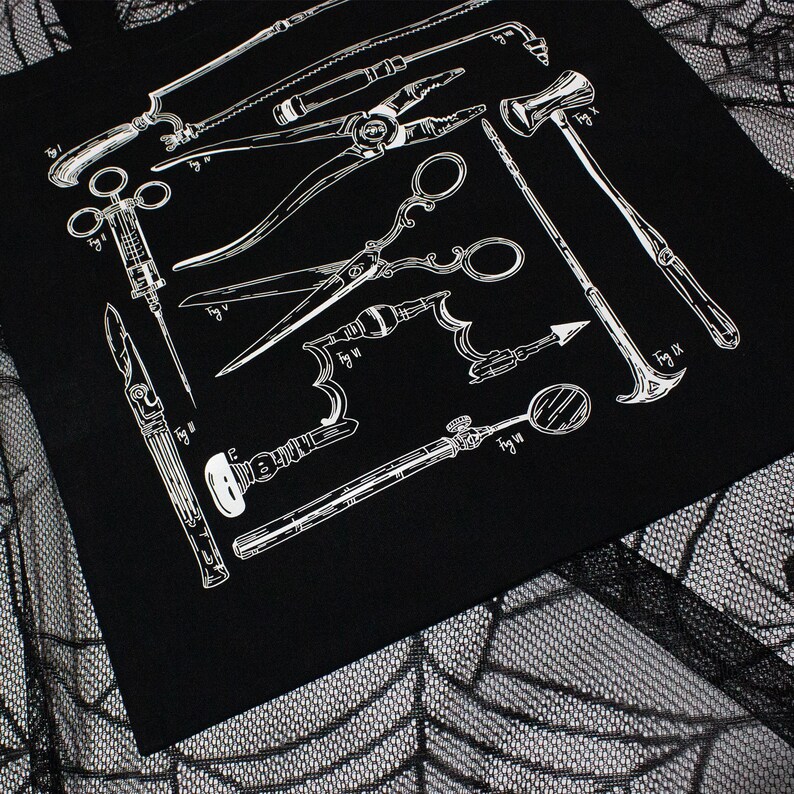 Schwarze Tragetasche mit einer weißen Illustration antiker chirurgischer Instrumente, darunter Sägen, Scheren und Spritzen. Das Design hat ein medizinisches Thema. Die Tasche ist aus dunklem Stoff.