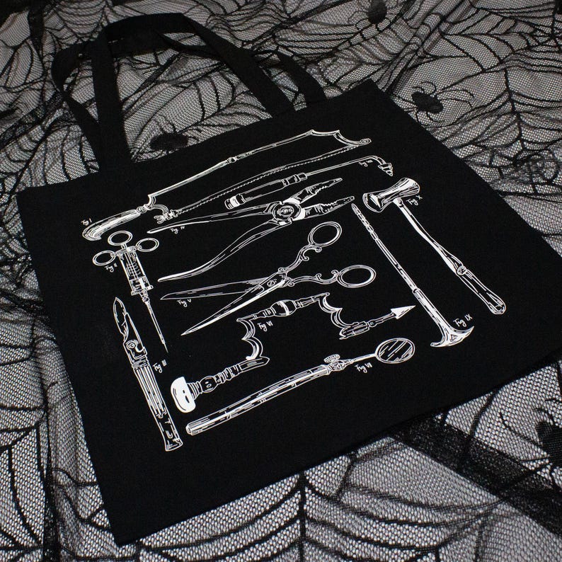 Schwarze Tragetasche mit einer weißen Illustration verschiedener chirurgischer Instrumente. Die Werkzeuge umfassen Sägen, Scheren und andere medizinische Instrumente. Die Tasche hat schwarze Griffe und besteht aus robustem Material.