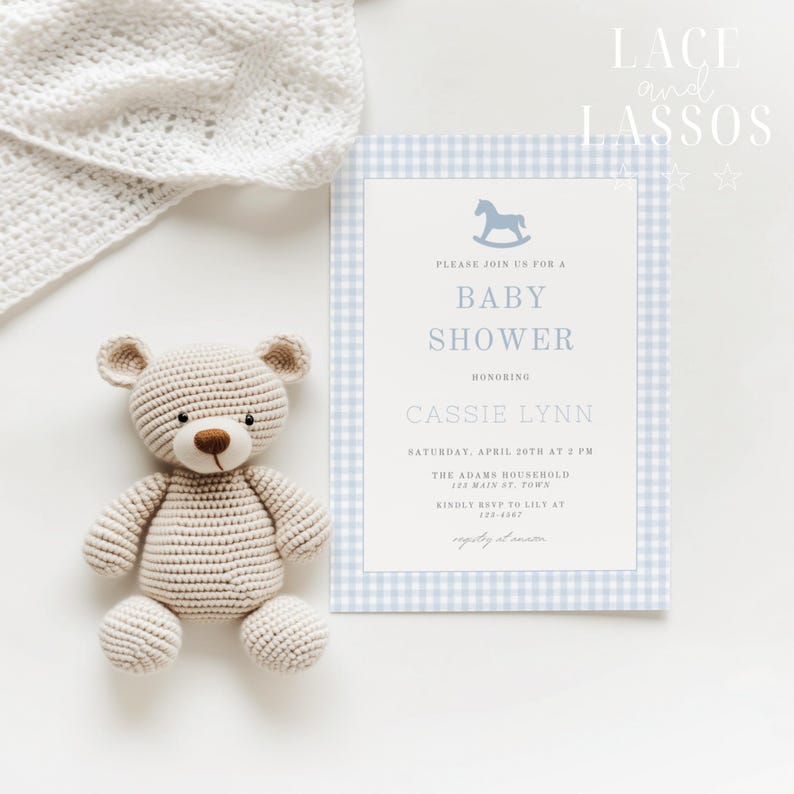 Puede incluir: Una invitaci&oacute;n a un baby shower con un borde de cuadros azules se muestra junto a un oso de peluche de ganchillo. La invitaci&oacute;n incluye detalles y dice "Baby Shower". Una manta blanca de ganchillo est&aacute; en el fondo. El texto "Lace and Lassos" est&aacute; en la esquina superior derecha.