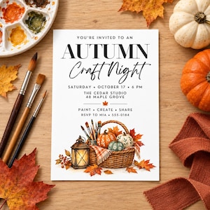 May include: A white rectangular invitation card with black text reading "YOU'RE INVITED TO AN AUTUMN CRAFT NIGHT" followed by event details. The bottom features a watercolor illustration of a wicker basket filled with pumpkins and paintbrushes.