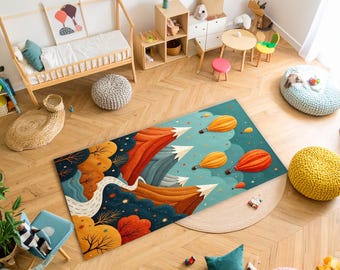 Puede incluir: Una colorida alfombra rectangular con un diseño de montaña y globo aerostático. La alfombra presenta tonos naranja, rojo y azul, con picos de montañas blancos y globos amarillos. La alfombra está colocada sobre un suelo de madera.