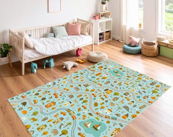Puede incluir: Alfombra rectangular con fondo azul claro que presenta una escena de ciudad con carreteras, casas, coches, árboles y un lago. La alfombra está colocada sobre un suelo de madera en una habitación infantil.