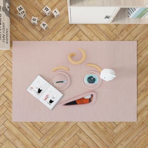 Leuk knipogend cartoon-gezichtskleed – zachte speelmat in 3D-stijl met grillige uitdrukking, pastelroze kinderkamertapijt met rubberen antislip achterkant