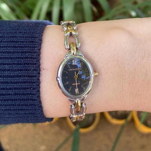 Reloj vintage Regno Chouchou RC26-3043H para mujer, con pulsera de dos tonos, esfera negra, números romanos, reloj de vestir ovalado, elegante joyería para mujer.