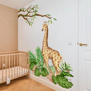 May include: A wall decal featuring a giraffe with a long neck and brown spots, surrounded by green tropical leaves and branches. The giraffe is standing near a crib in a nursery setting.