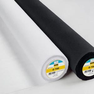 Könnte beinhalten: Zwei Stoffrollen, eine weiße und eine schwarze, werden auf einer weißen Oberfläche gezeigt. Die Rollen sind mit dem Text "G 700" und einem Barcode versehen. Der Stoff scheint ein mittelschweres Material zu sein, das sich für verschiedene Nähprojekte eignet.