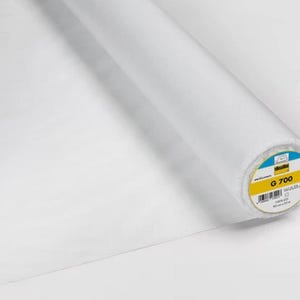 Könnte beinhalten: Eine Rolle weißen Stoffes, teilweise abgerollt, vor weißem Hintergrund. Das Ende der Rolle zeigt ein Etikett mit dem Text "G 700". Der Stoff scheint ein Vliesstoff zu sein.