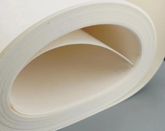 May include: A rolled stack of off-white paper, with visible layers and a curved shape. The paper appears to be thick and textured, with a soft, neutral color. The image is a close-up, highlighting the paper's texture and form.