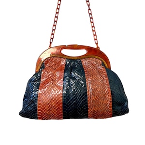 以下が含まれることがあります： 茶色と黒のヘビ革模様のヴィンテージハンドバッグ。バッグは茶色のハンドルとチェーンストラップが特徴です。デザインは茶色と黒の縦縞模様で、印象的な視覚的コントラストを生み出しています。