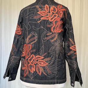 May include: A dark denim jacket with orange floral embroidery. The jacket features a classic collar, button cuffs, and a button-down front. The embroidery includes detailed leaves and flower designs, with measurements in cm.