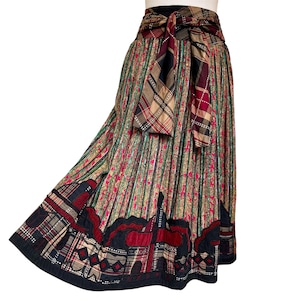 Peut inclure: Longue jupe à motifs avec un design unique. La jupe présente des rayures verticales, des motifs floraux et une ceinture à carreaux. L'ourlet est orné d'une bordure géométrique détaillée en noir, rouge et beige. La jupe mesure environ 90 cm de long.