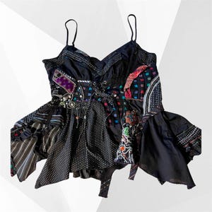 Könnte beinhalten: Schwarzes Patchwork-Top mit Spaghettiträgern, V-Ausschnitt und Schnürung vorne. Das Top weist verschiedene Muster auf, darunter Punkte, Streifen und bunte Quadrate, mit dekorativen Verzierungen.