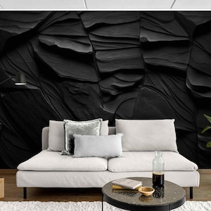 Könnte beinhalten: Ein modernes Wohnzimmer mit einem weißen Sofa, Kissen und einer schwarzen, strukturierten Wand. Ein runder Couchtisch, eine Stehlampe und eine Topfpflanze ergänzen die Szene. Die Wand hat ein einzigartiges, geschichtetes Design.