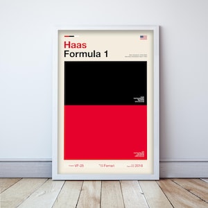 May include: Framed poster featuring the Haas Formula 1 team. The design is split into black and red sections with the team name and logo in red. Includes the American flag and team details.