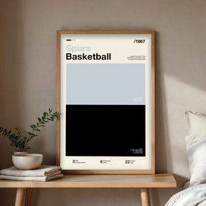 May include: A framed poster with a minimalist design. The poster features the text "Spurs Basketball" above a light blue and black color block. Additional text includes "/1967" and details about the team's championships and division.