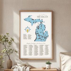 Op de afbeelding: Een ingelijste print getiteld "Brewery Tour of Michigan" toont een lichtblauwe kaart van Michigan met bierglaspictogrammen die brouwerijen markeren. De print bevat een lijst met brouwerijen en de tekst "Explore Michigan - One Pint at a Time."